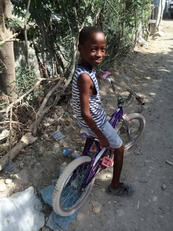 A boy riding his bike around Camp ACRA, a tent city within Petion-ville, Haiti, stops for a photo.A boy riding his bike around Camp ACRA, a tent city within Petion-ville, Haiti, stops for a photo. Seniors Marie DeShetler and Lia Whitney are now expanding the Haiti Solidarity Club to include a Middle College branch. Photo courtesy Marie DeShetler.