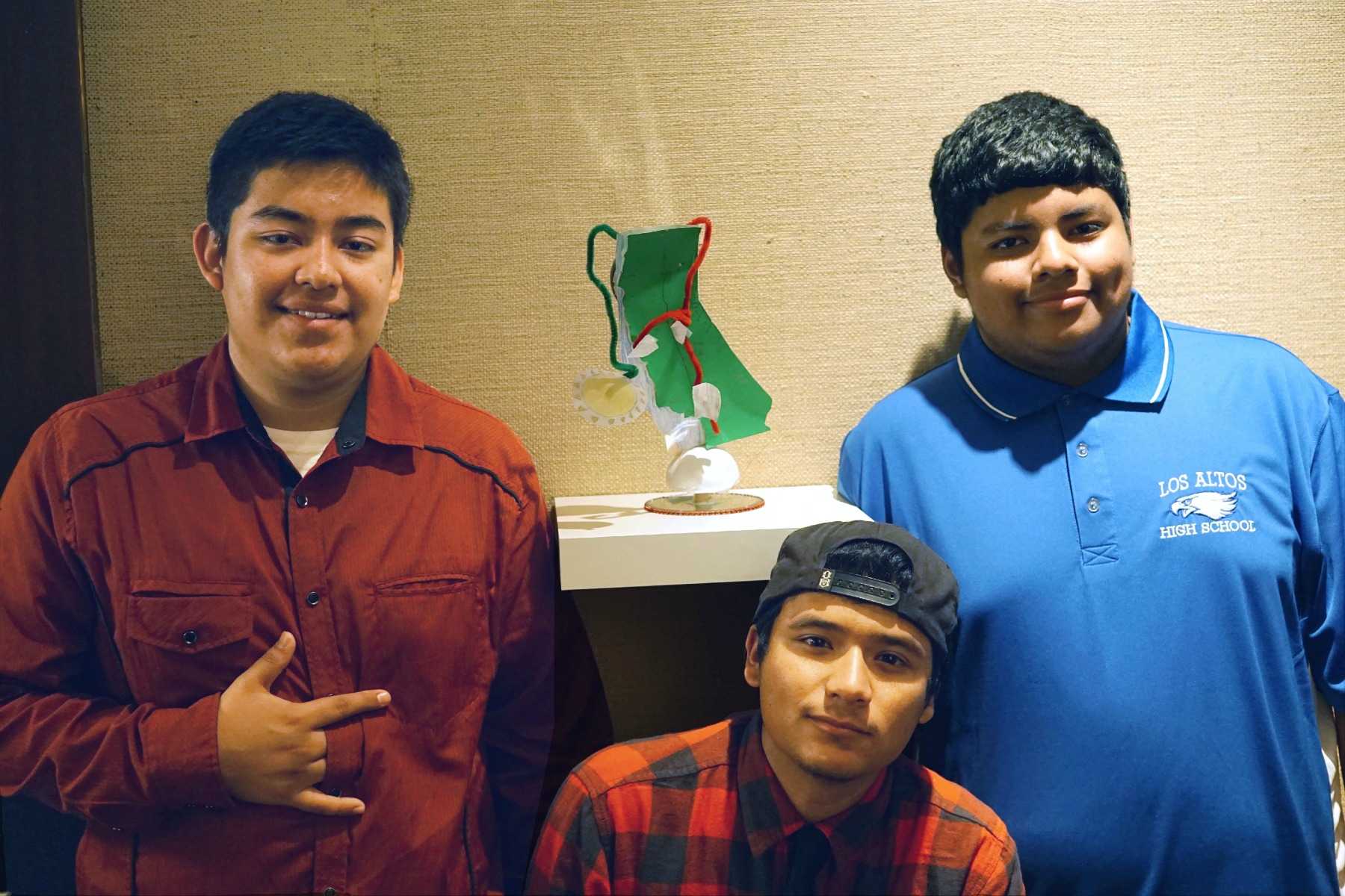 Juniors Ronaldo Flores, Martin Quezada and Luis Arias Diaz pose next to their artwork. The environmental science class's artwork is currently being featured in the
