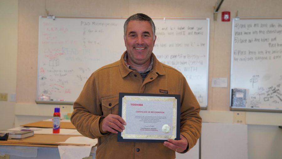 Biology teacher Jacob Russo holds up the certificate for the $5000 grant he received from the Toshiba Foundation. The money will be used to purchase DNA processing equipment for his new lab which will investigate the evolution of sleep mechanisms.