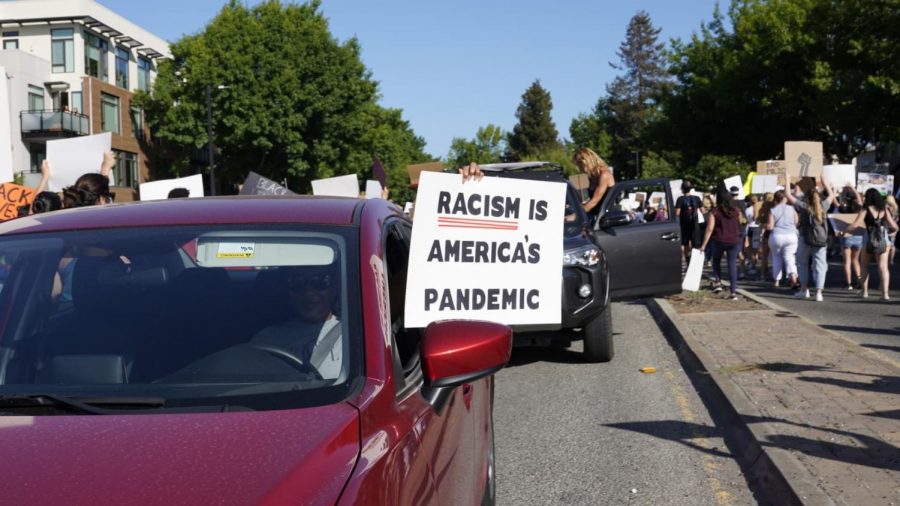 Drivers raise signs from their cars as protesters march along El Camino.