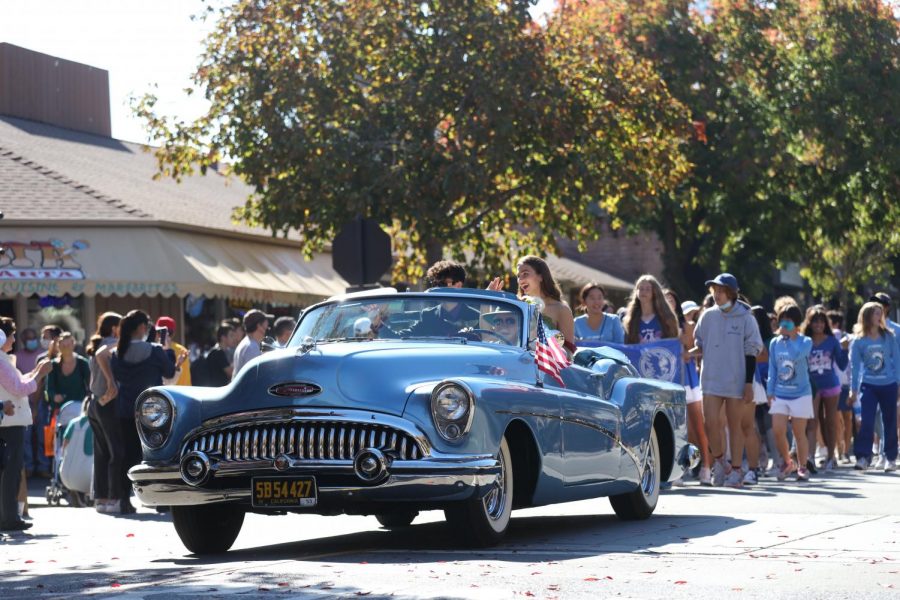Seniors Serena Gaylord and Oliver Breitbart wave to community members as students parade behind them at the 2021 LAHS Homecoming parade in downtown Los Altos. The parade was one of the first school and community wide events to be hosted since the COVID-19 lockdown.
