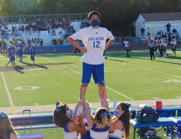 Sreyas stands as a flyer at a football game.