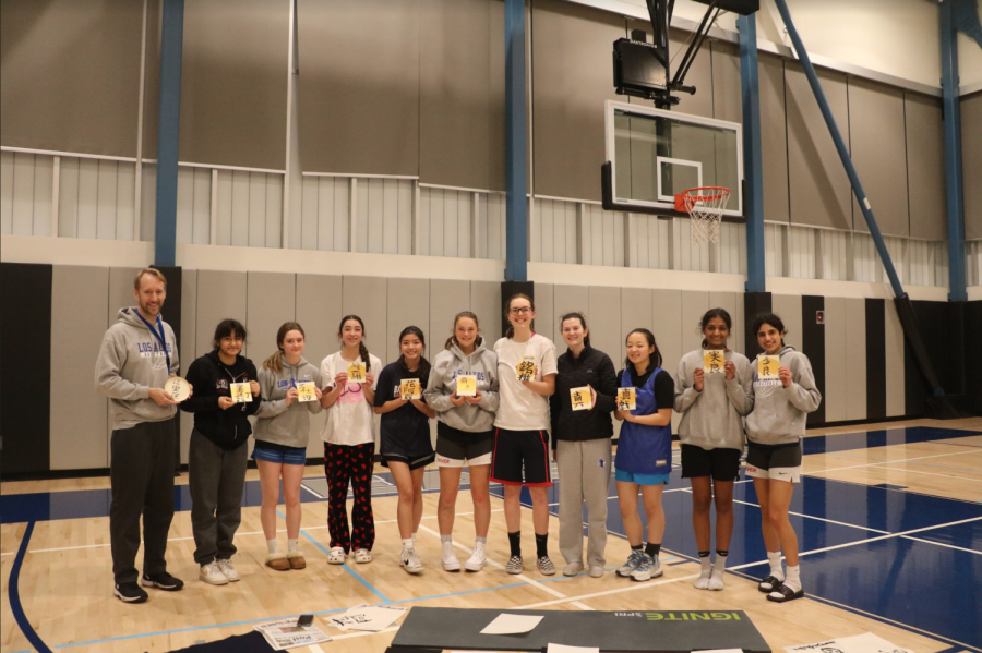 The varsity girls basketball team poses with their artwork after practicing Japanese calligraphy after practice. This team bonding activity was hosted by junior Chihiro Niki and her mom, Chiharu Niki.