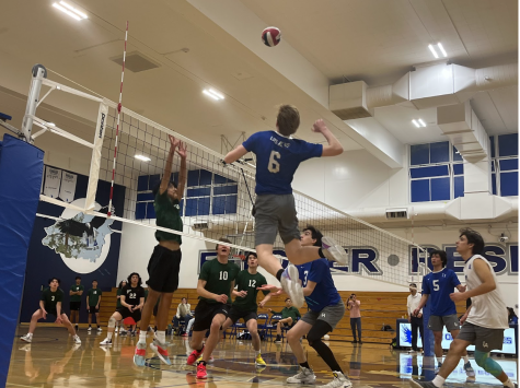 Junior outside hitter Aidan Cuppett takes a swing, surrounded by his teammates of the varsity boys volleyball team.