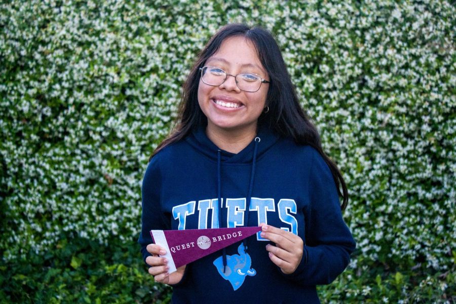 LAHS senior Areli Aguilar Garcia posing in her Tufts University sweatshirt with a Questbridge flag. Areli was accepted to Tufts as a Questbridge scholar, which grants her a full-ride scholarship. 