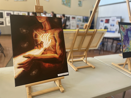 A painting by Taeva Wegbreit depicts a glowing hand pressed against a figure’s chest. NAHS hosted an art auction and exhibition Sunday, November 4.