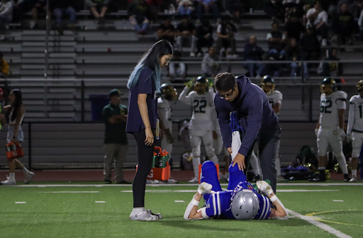 LAHS athletic trainer Lucas Okuma and ESMT PR Director Krystal Zhu help an injured football player.