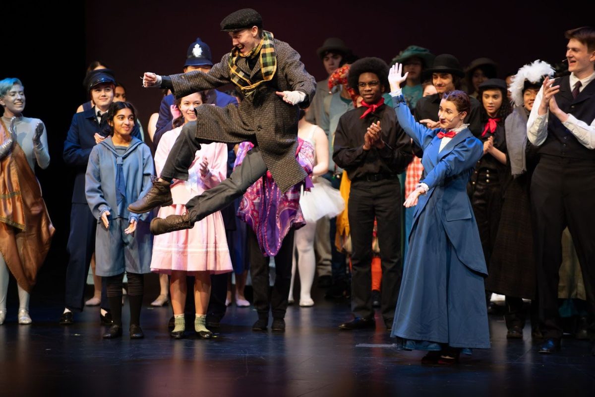 At Curtain Call, senior Connor Volkert (Bert) clicks his heels midair while senior Tessa Prodromou (Mary Poppins) stands to his left. 