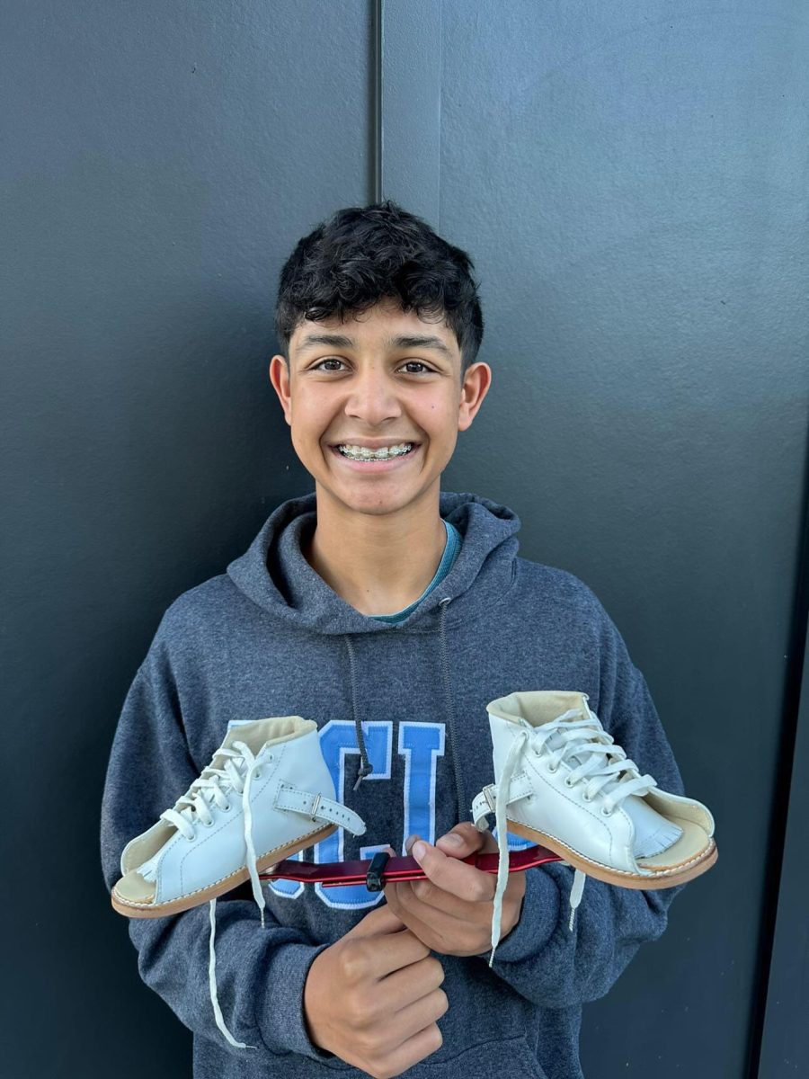 Sophomore Shaan Bhatia holds shoes he once had to wear for clubfoot. 