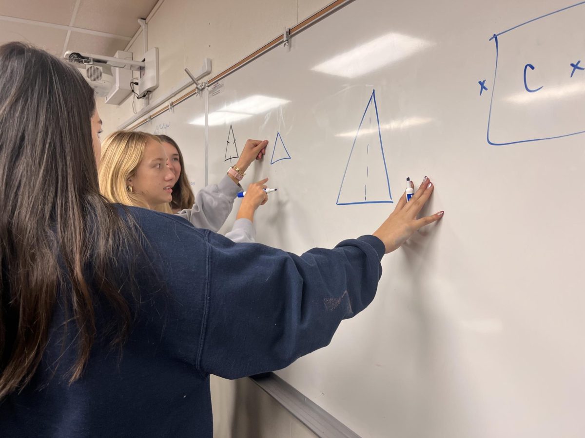 Students work through a math problem on the board. At Breakfast Club, students go for the math but always stay for the laughs.
