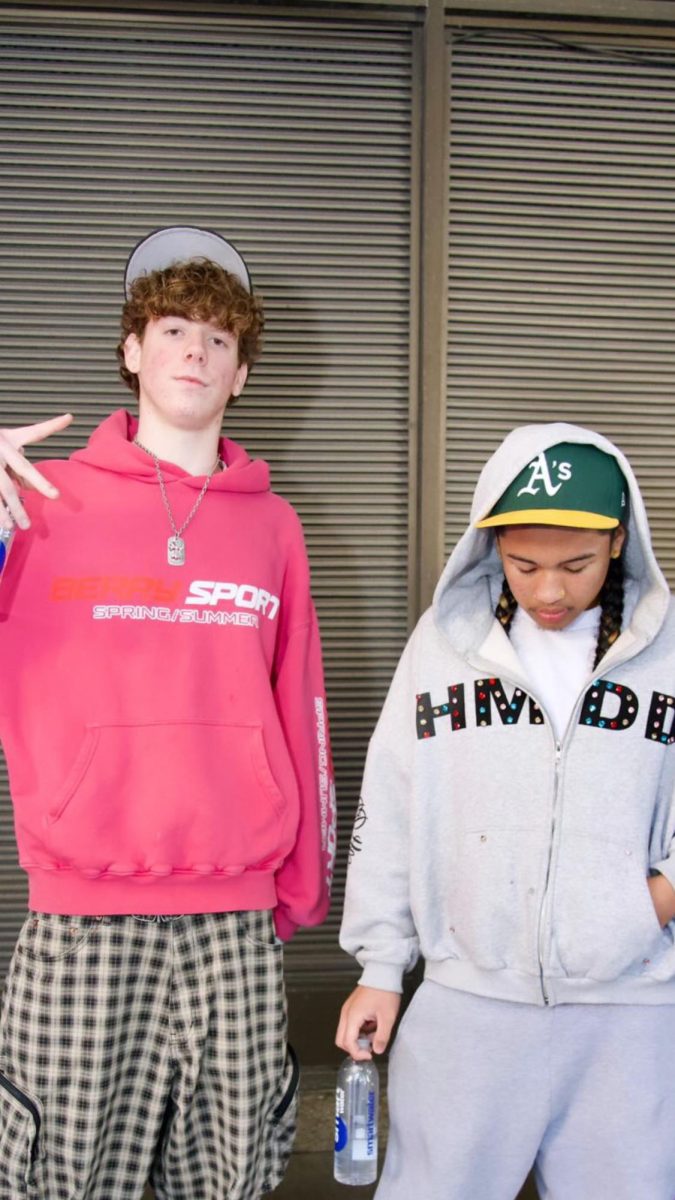 Isaiah poses Caption: Isaiah Somera (right) poses for a photoshoot in an Oakland A’s baseball cap and a Happy Memories Don’t Die hoodie. 