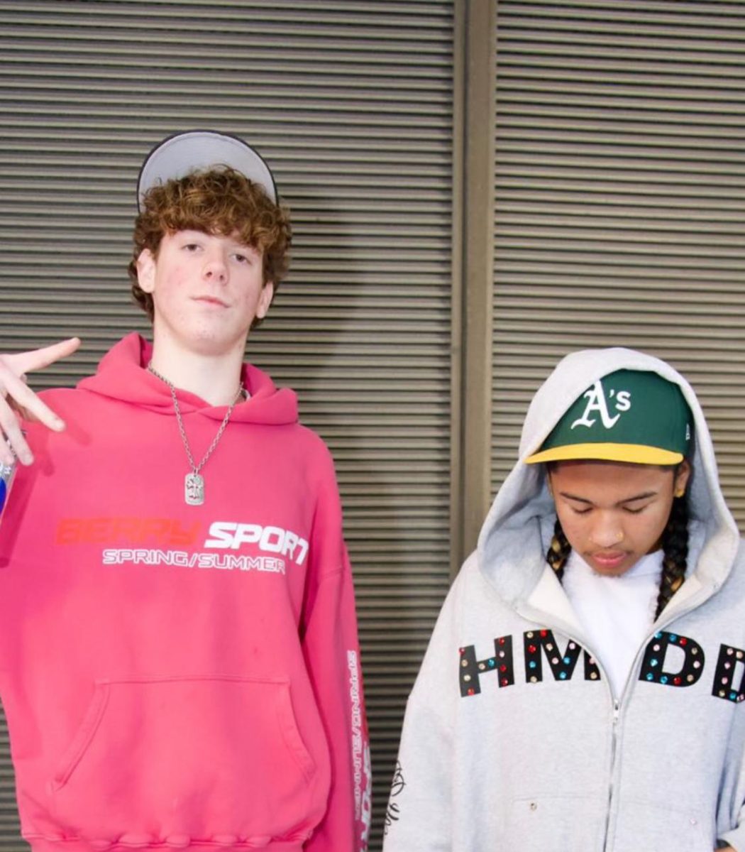 Isaiah poses Caption: Isaiah Somera (right) poses for a photoshoot in an Oakland A’s baseball cap and a Happy Memories Don’t Die hoodie. 