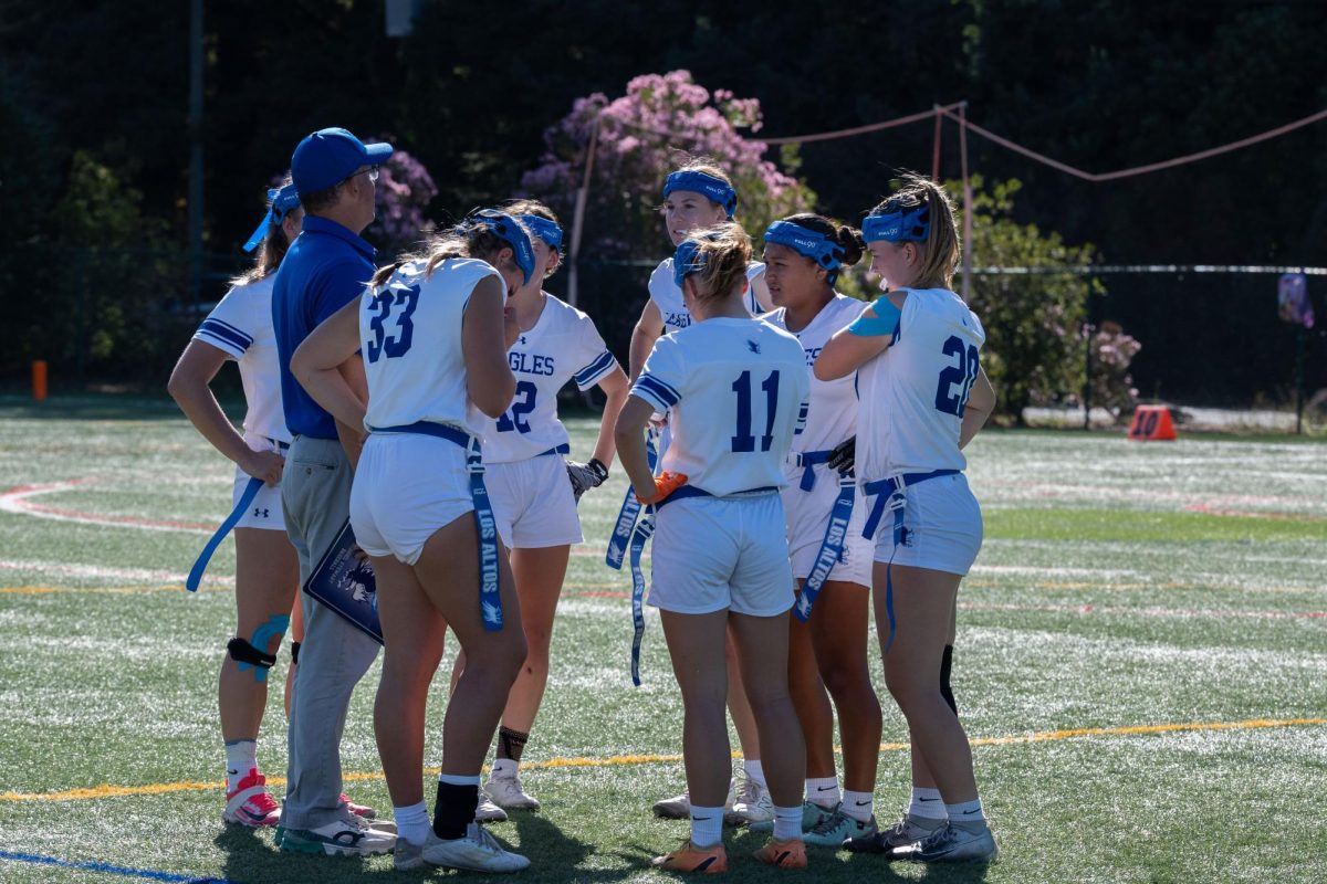 Varsity girls flag-football huddles during halftime against Menlo School. Their record now stands at 10-4 overall and 2-1 in league.