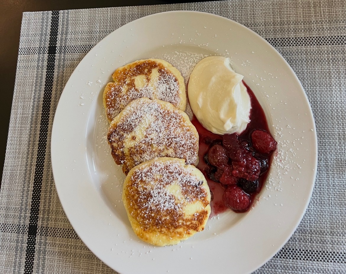 Lukianna's cottage cheese pancakes sit plated with rasberry collee and a dollop of whipped cream.