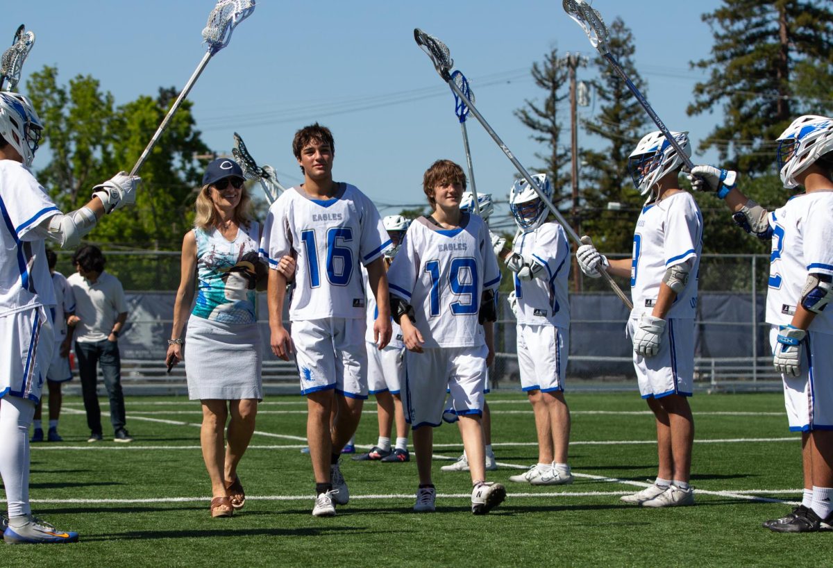 Senior Martin Koinov, joined by his family, walks through a tunnel of lacrosse sticks in celebration. On Tuesday, May 7, the Los Altos High School varsity lacrosse team swept the Hillsdale High School Knights 14–1 in a senior night rematch. 